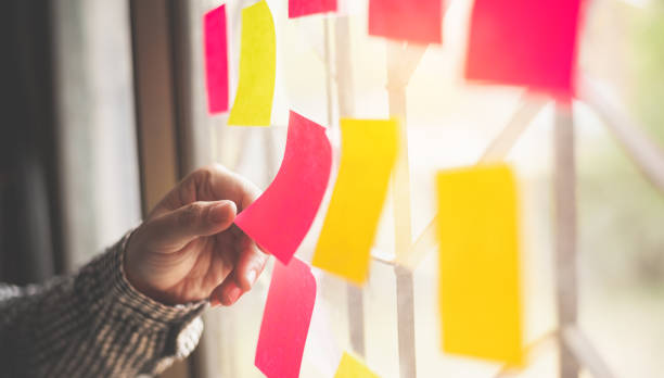 istock hand is holding the post it notes attached to the glass wall. Concept brainstorming, share idea. 1230231000