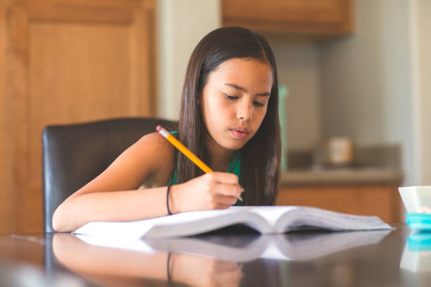 istock Young Girl Sitting At A Desk And Working On Her Homework 1230287808