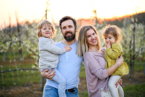istock Family with two small children standing outdoors in orchard in spring. 1230299255