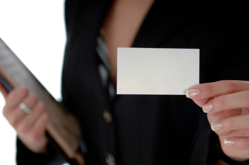 Businessman in suit holding an empty business card in front of him. Selective focus on foreground.