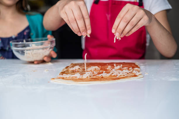 istock Close up girls hands making pizza 1230665313