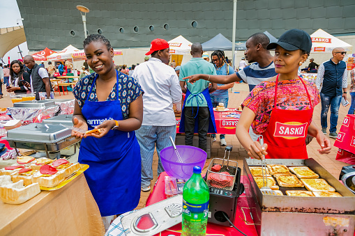 Soweto, South Africa - September 17, 2017: Diverse African vendors cooking and serving various bread based street food at outdoor festival