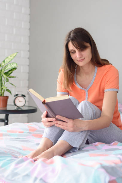 istock Girl at home sitting on the bed and reading a book 1230723092