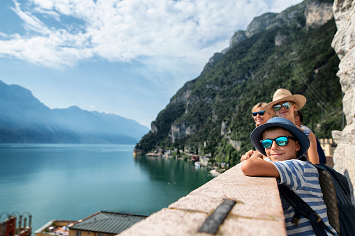 Family enjoying vacations in Italy. They are looking at the panorama of Riva del Garda and Lake Garda surrounded my mountains.\nNikon D850