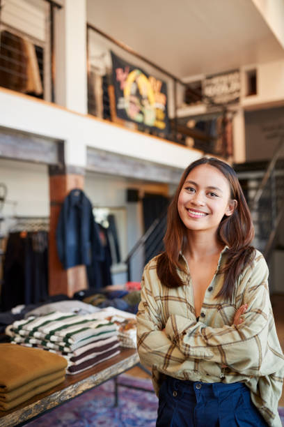 portret uśmiechniętej właścicielki sklepu mody stojącej przed wyświetlaczem odzieżowym - clothing store sales clerk usa clothing zdjęcia i obrazy z banku zdjęć