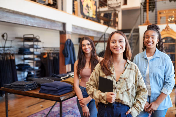 portret uśmiechniętego wielokulturowego zespołu sprzedaży kobiet w sklepie mody przed wyświetlaczem odzieżowym - clothing store sales clerk usa clothing zdjęcia i obrazy z banku zdjęć