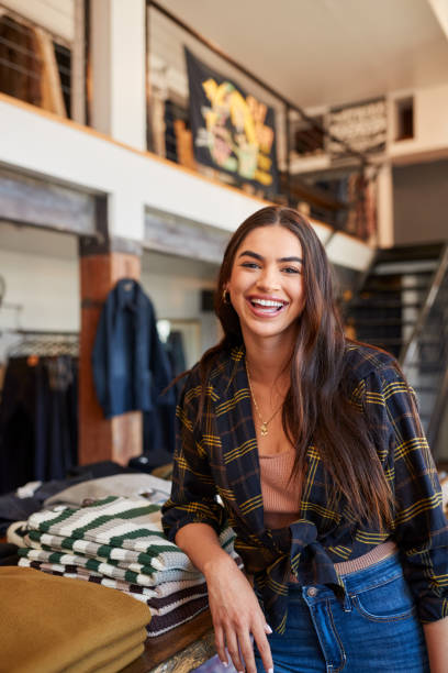 portret uśmiechniętej właścicielki sklepu mody stojącej przed wyświetlaczem odzieżowym - clothing store sales clerk usa clothing zdjęcia i obrazy z banku zdjęć