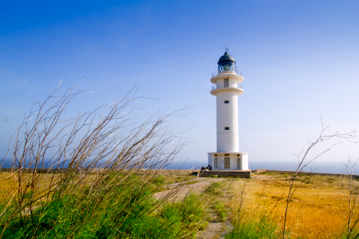 In this expansive view, the När Fyr, also known as Nar Lighthouse, stands prominently on Närsholmen in southeastern Gotland. It serves as a commanding focal point against a wide, panoramic seascape that stretches out to meet the sky at the distant horizon. The lighthouse, an iconic maritime guide, adds a sense of place and purpose to the endless expanse of water and sky, creating a compelling contrast between human-made structure and the untamed natural elements. The broad scope of the seascape serves to emphasize the vastness of the ocean, making the lighthouse appear both significant and yet humblingly small in the grand scheme of the natural world. This visually striking composition captures the serenity and grandeur of the coastal landscape, blending both the intricate details of the built environment with the boundless beauty of the maritime horizon.