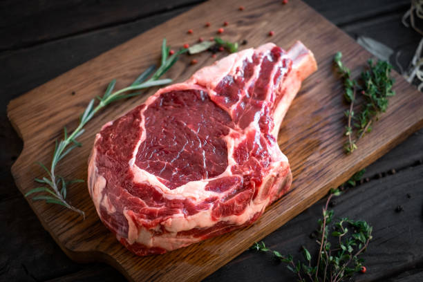 木製のまな板の骨に生のリブアイステーキプレミアムビーフ - rib eye steak beef cutting board meat ストックフォトと画像