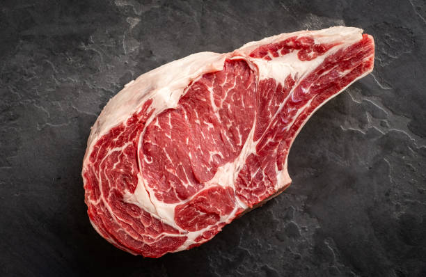 石の背景に生のカウボーイステーキ、骨のプライムリブアイ、トップビュー - raw meat steak beef ストックフォトと画像
