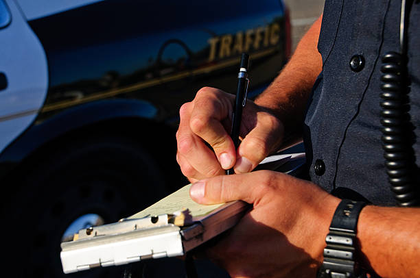 Writing a ticket A police office on the side of the road as he writes a ticket. police car photos stock pictures, royalty-free photos & images