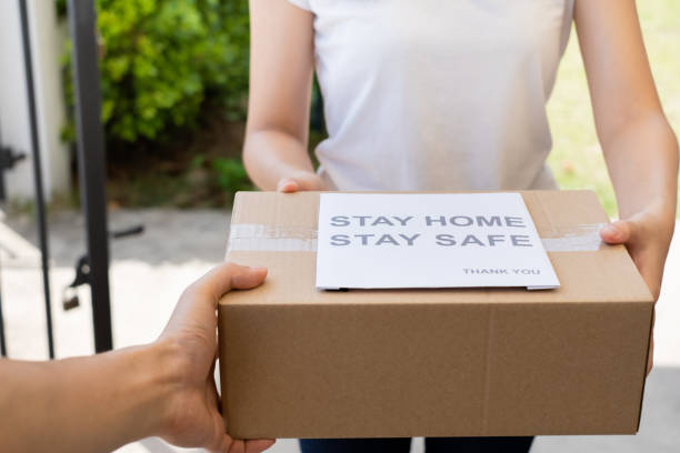 istock Delivery service male in uniform give cardboard box package to receiver customer client front home, fast express offsite when crisis coronavirus, covid19 new normal lifestyle concept. 1230923000