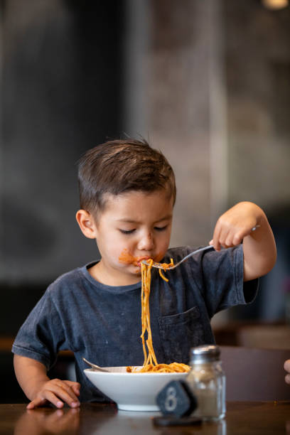 私のスパゲッティを楽しむ - child eating pasta spaghetti ストックフォトと画像