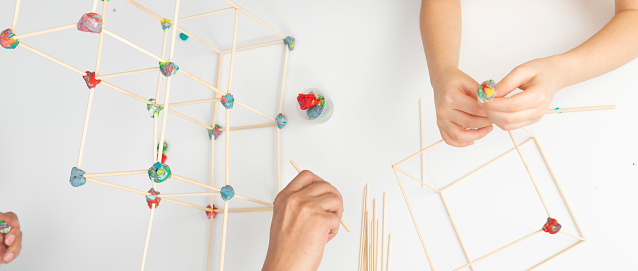 Father and daughter building construction with cubes made of craft sticks and play dough.