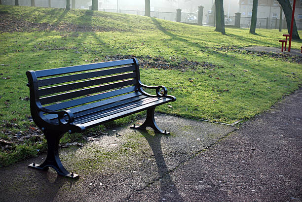Wooden bench near frozen river in early winter morning.