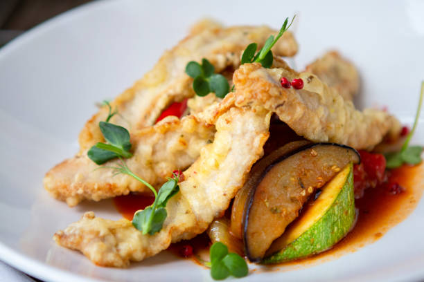 istock white fish fried in slices with vegetables on a white plate 1230943459