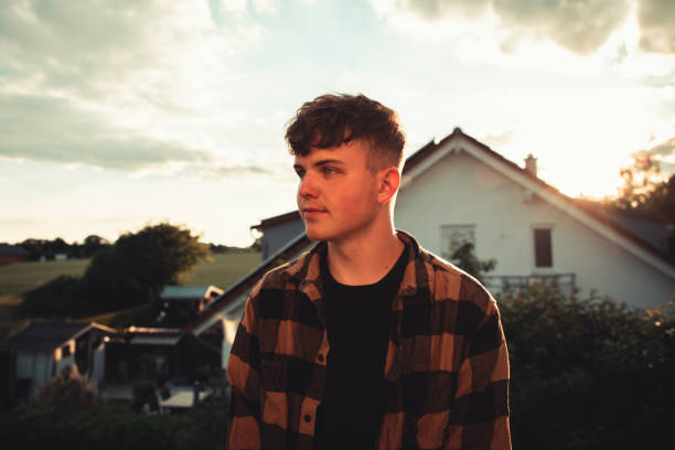 Suburbia Teenage Man Outdoors Lifestyle Portrait Young teenage man standing outdoors in his residential suburban district in sunset light. Suburbia Millennial Youth Culture Outdoor Portrait. reutlingen photos stock pictures, royalty-free photos & images