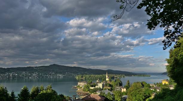 Panoramaview of Maria Wörth with the iconic church and lake Woerthersee View of Maria Wörth with clouds dramatic light from a nearby hillside maria woerth stock pictures, royalty-free photos & images