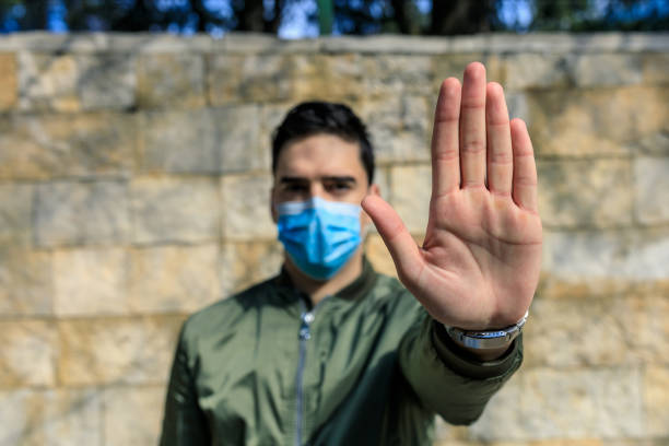 istock Stop the infection! Man with a mask gesturing stop 1230985511