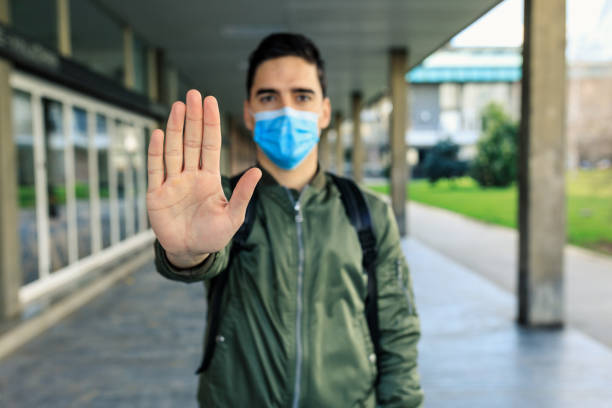istock Stop the infection! Man with a mask gesturing stop 1230994637