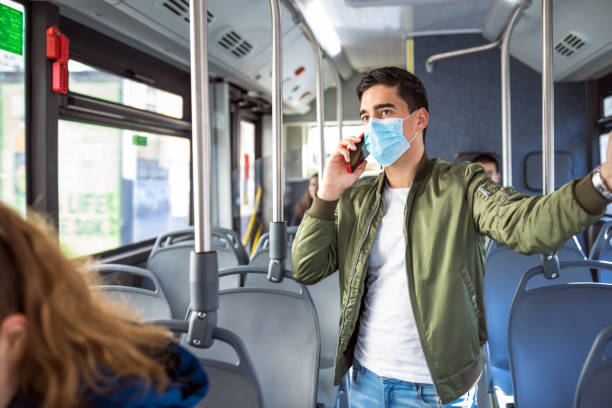 istock Man talking on the phone in the bus while wearing medical mask 1231017776