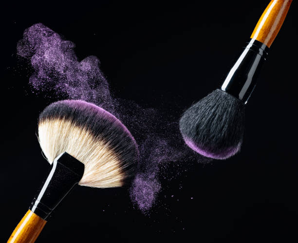 istock Makeup concept with a  professional makeup brushes with glowing purple eye shadow isolated on black background. 1231101309