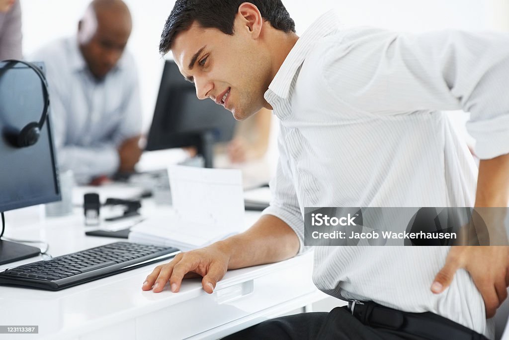 Backache Young business man holding his lower back at work 30-39 Years Stock Photo