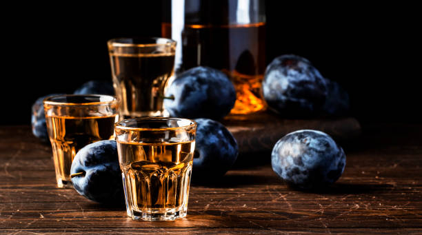 slivovica - plum brandy or plum vodka, balkan hard liquor, strong drink in shot glasses on old wooden table, copy space - slivovitz imagens e fotografias de stock
