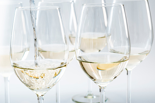 Wine being poured into glass, several glasses are already poured, studio shot.
