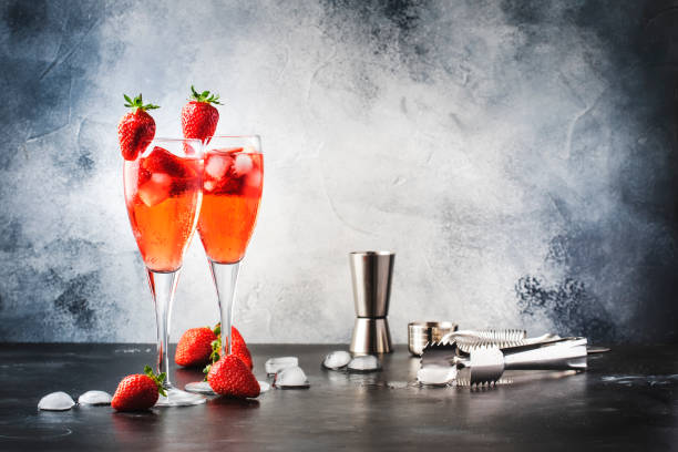 Rossini italian red alcoholic cocktail with sparkling wine, strawberry puree and ice in champagne glasses, copy space