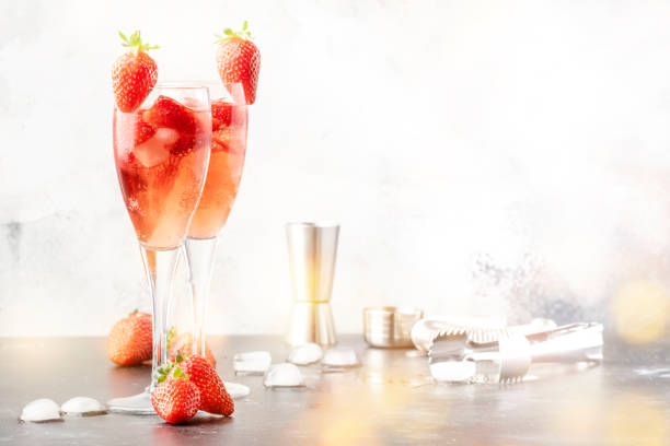 Rossini italian red alcoholic cocktail with sparkling wine, strawberry puree and ice in champagne glasses, copy space