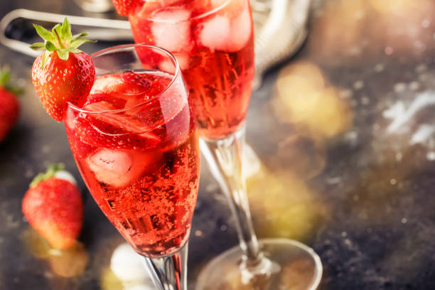 Rossini italian red alcoholic cocktail with sparkling wine, strawberry puree and ice in champagne glasses, copy space