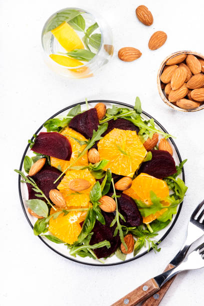 istock Beetroot Salad with Orange, arugula and almonds nut on white background. Vegan healthy summer food. Top view. Copy space 1231188806