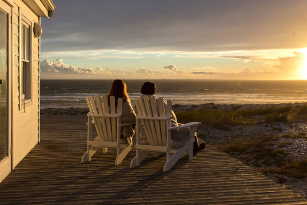 couples romantiques appréciant le coucher du soleil à la maison de plage - beach house photos et images de collection