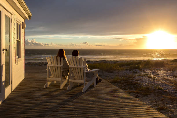 couples romantiques appréciant le coucher du soleil à la maison de plage - atlantic coast flash photos et images de collection