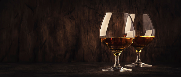 Cognac in a glass, dark background, banner with copy space