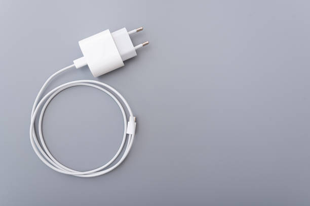 White adapter charger with usb charging cable on gray surface, top view White adapter charger with usb charging cable on gray surface, top view connection block computer cable electronics industry electricity stock pictures, royalty-free photos & images