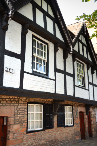 The historic Victorian buildings in Chester known as 'The Nine Houses'. This photograph also includes the plaque with SMP written on it designating St Michaels Parish. The windows and brick-work can clearly be seen along with the classic black and white style timber structure.
