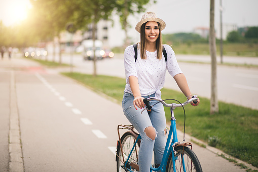 Pretty young woman is riding on bicycle in the city.