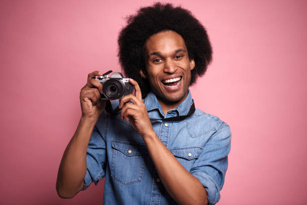 istock Portrait of a smiling man with camera in studio shot. 1231456712