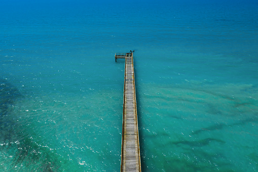 Top down view of pier in turquoise water.