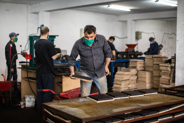 istock Man arranging cube shape briquettes for hookah in factory 1231502514