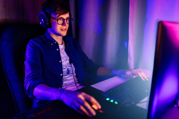 istock gamer playing video games on a computer with headphones and using a colorful backlit keyboard 1231544050
