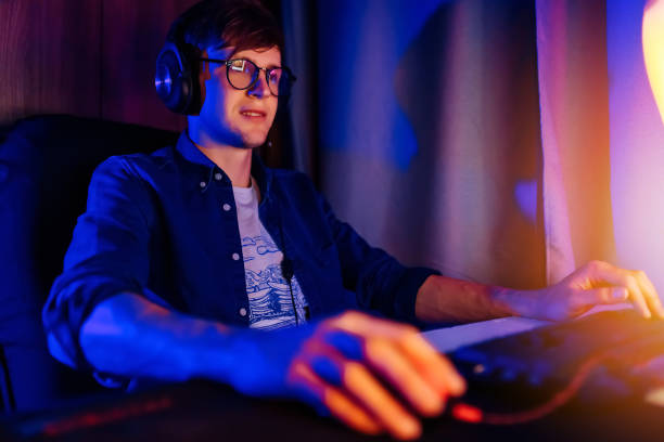 istock gamer playing video games on a computer with headphones and using a colorful backlit keyboard 1231546087