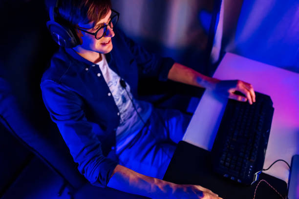 istock gamer playing video games on a computer with headphones and using a colorful backlit keyboard 1231547493