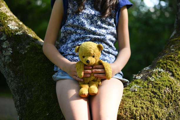 Teddy bear embraced by a child