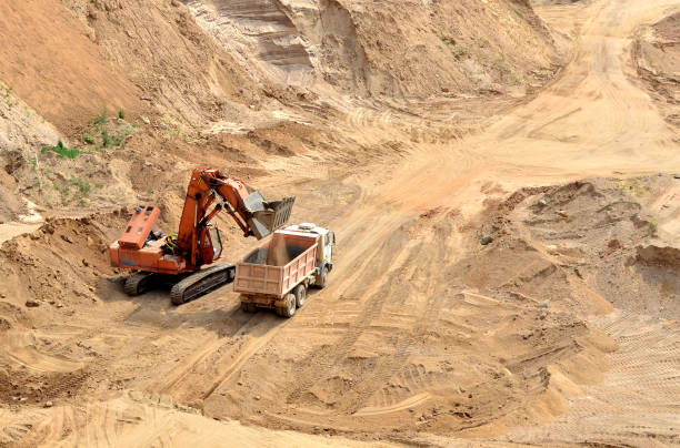istock Excavator loading sand in to the heavy dump truck at mining quarry 1231582543