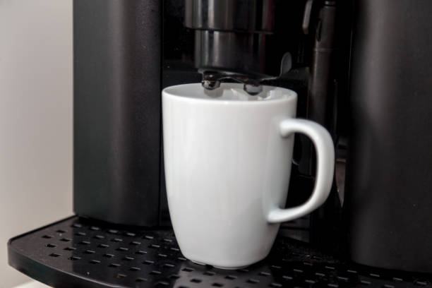 istock Coffee maker pours coffee into mug. Coffee maker pours freshly brewed hot coffee into white Cup 1231602237