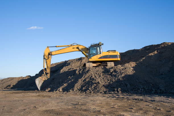 istock Excavator working at construction site. Backhoe digs ground in sand quarry on blue sky background. Construction machinery for excavation, loading, lifting and hauling of cargo on job sites 1231611621