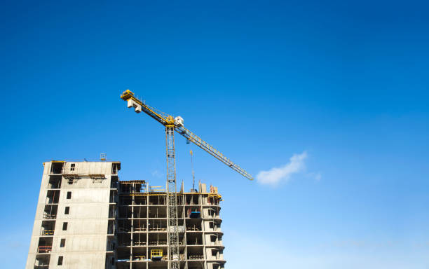 istock Tower cranes constructing a new residential building at a construction site against blue sky. Renovation program, development, concept of the buildings industry. 1231641805
